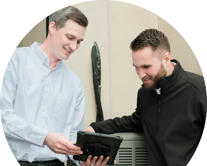 A Shines technician in a white shirt shows service details on a tablet to a smiling client in a black jacket, standing beside an AC unit outside a beige building. A Shines technician in a white shirt shows service details on a tablet to a smiling client in a black jacket, standing beside an AC unit outside a beige building.