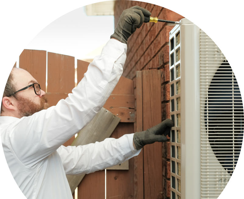 Shines service personnel working on an AC condenser, using a screwdriver to secure the unit’s panel outdoors beside a wooden fence. Shines service personnel working on an AC condenser, using a screwdriver to secure the unit's panel outdoors beside a wooden fence.