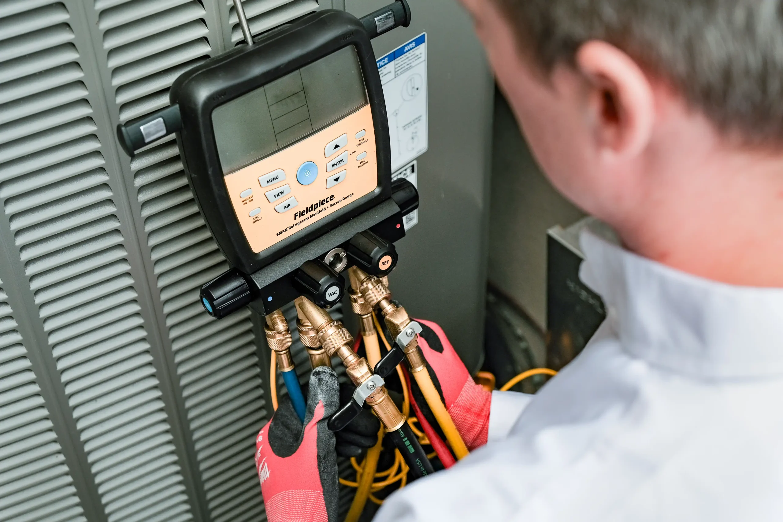 Shines Energy technician testing an outdoor heat pump with a digital manifold to confirm performance before fall nor’easter storms in coastal Nova Scotia.